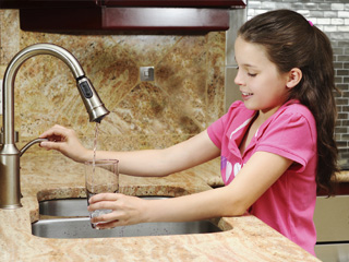 Girl using faucet to fill a glass of water