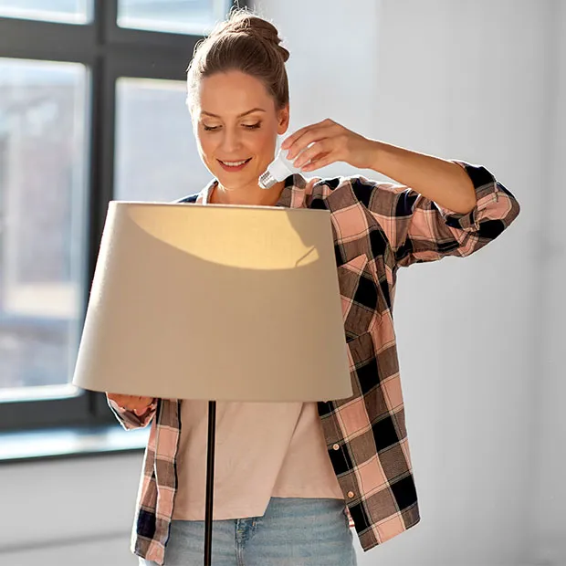 A woman pulling a lightbulb out of a lamp, as she packs up to move.