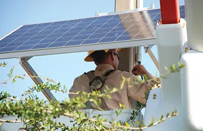 Line worker pictured below a solar panel on a post