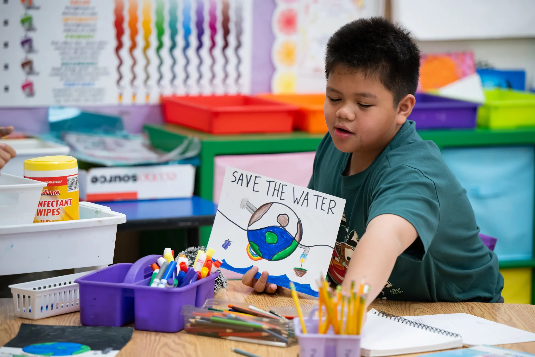 Student working on OUC's water conservation calendar project, holding his artwork